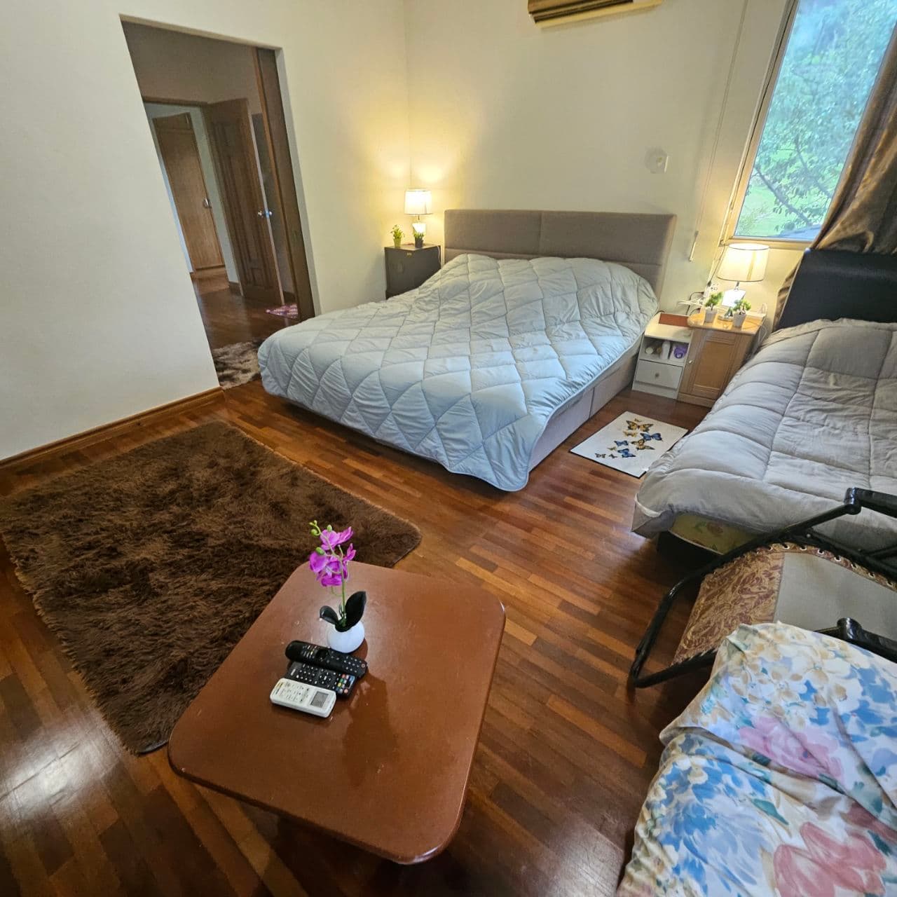 Bedroom with a light blue quilted bed, brown shag rug, and small wooden coffee table.