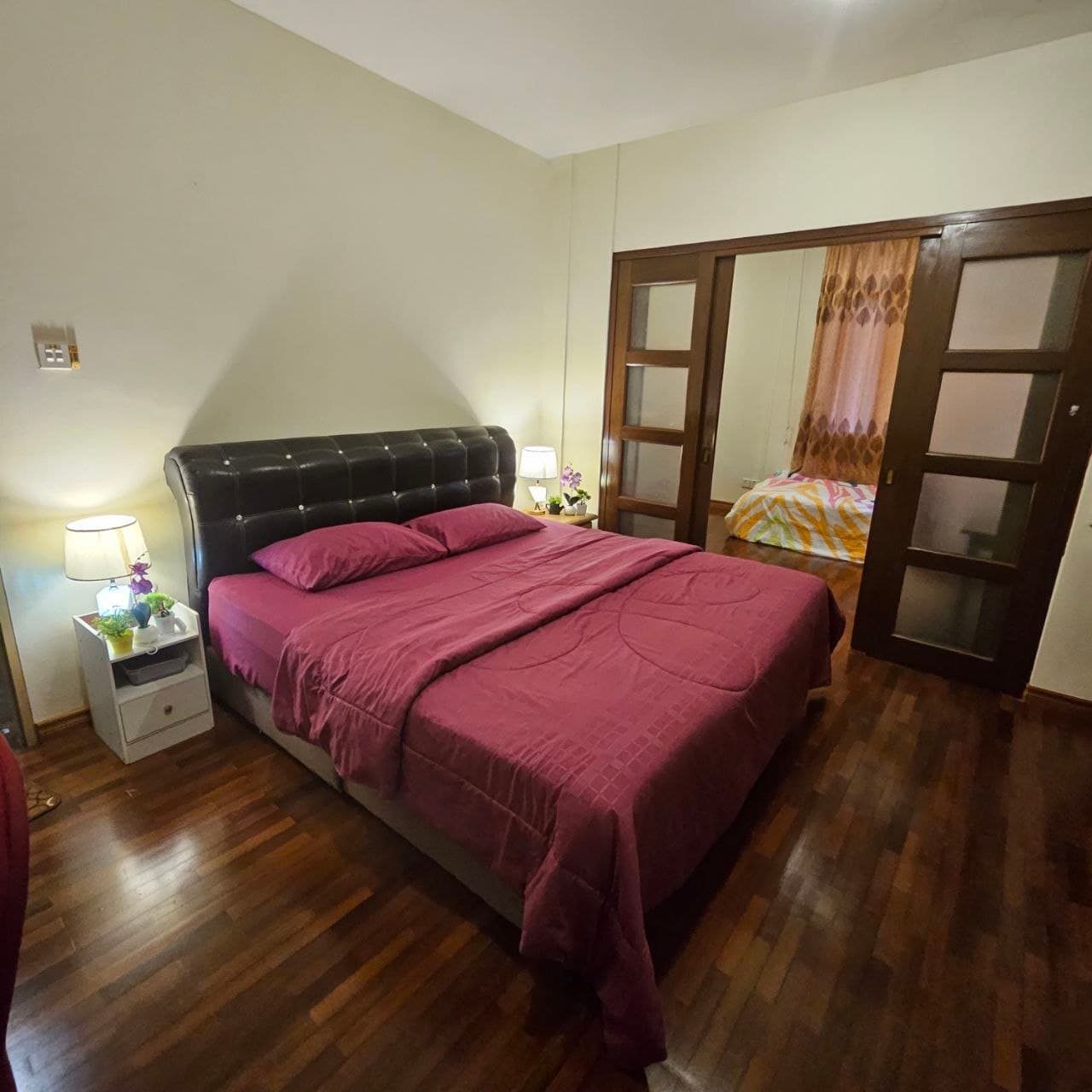 Bedroom with a maroon bed, tufted headboard, and sliding doors to an adjacent room.