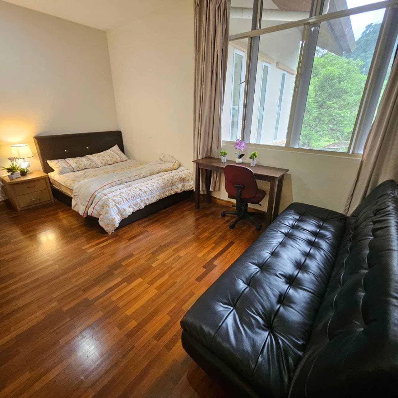 Bedroom with hardwood floors, a bed, a desk, and a black tufted leather sofa.